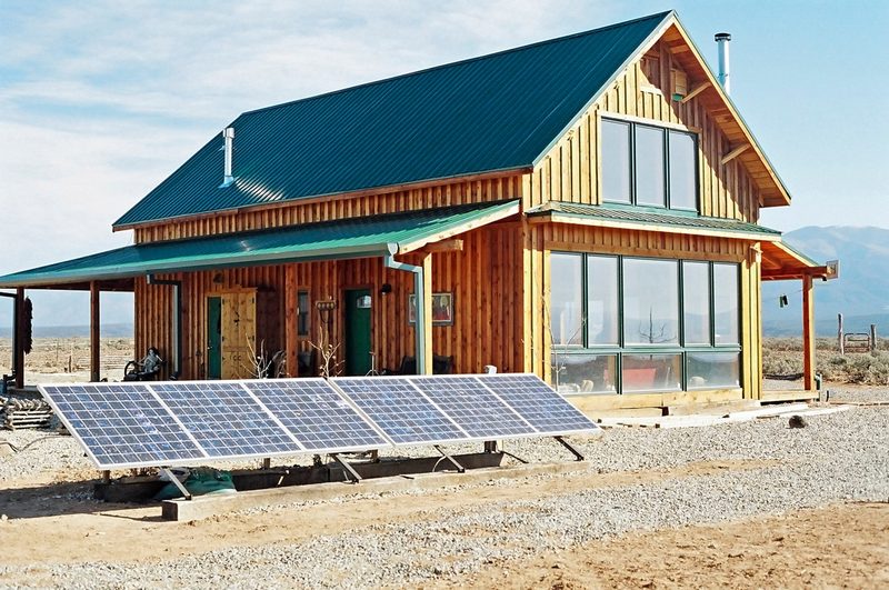 Timber off-grid cabin with a ground-mounted solar array in the desert