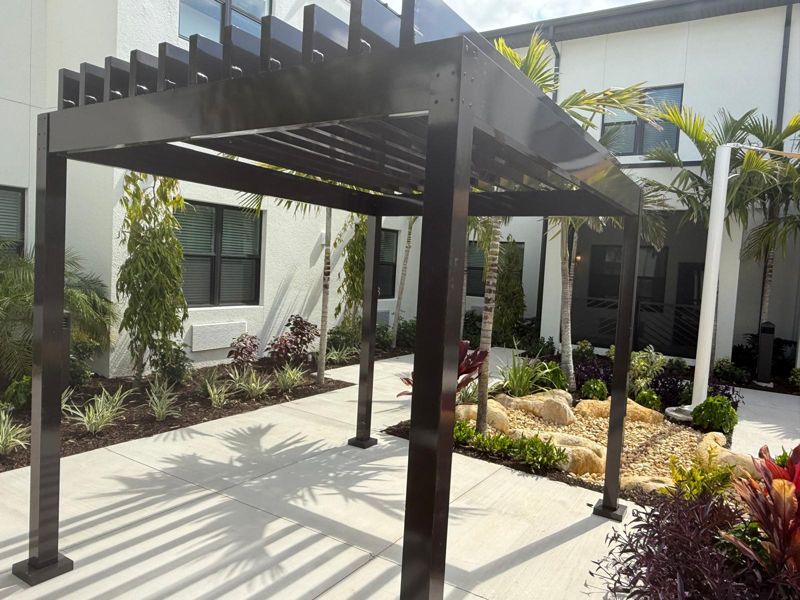 Bronze metal pergola over a front walkway in Naples, Florida