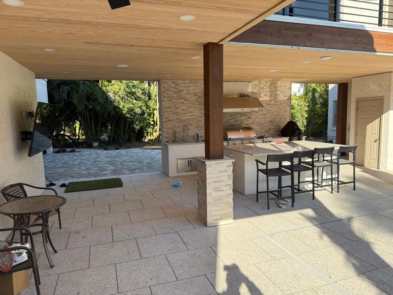 Covered outdoor kitchen with a stone column and bar seating in Tampa, Florida