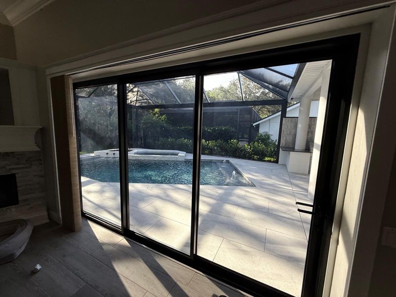 Large black-framed sliding glass doors opening to a screened pool in Tampa, Florida